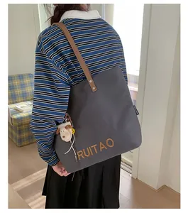 Détail du sac cabas en toile grise avec broderie marron et breloques décoratives