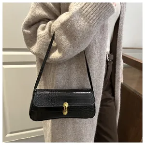 Detail view of black crocodile pattern baguette bag with gold metal buckle on model