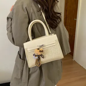 Detail of straw woven handbag with cream leather flap and leopard bow plush charm