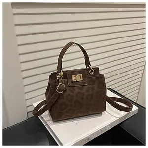 Détail du sac seau à imprimé léopard avec ferrures dorées sur fond de bois blanc