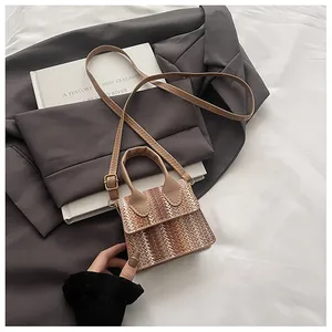 Detail of woven gradient chevron pattern bag with leather handle and gold hardware