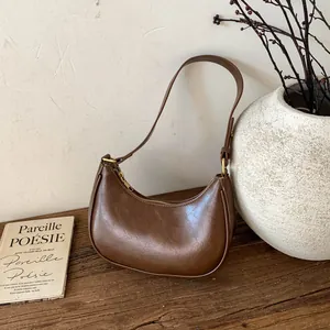 Détail du sac demi-lune marron en cuir brillant avec accessoires dorés chics