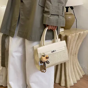 Detail of cream tote bag with straw texture stitching and cute bear charm pendant