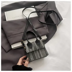 Detail of mini crossbody bag with black and white woven texture and gold metal hardware