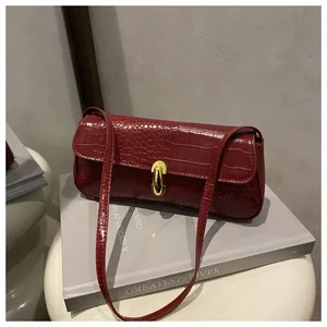 Macro detail of wine red crocodile texture on faux leather bag with gold buckle