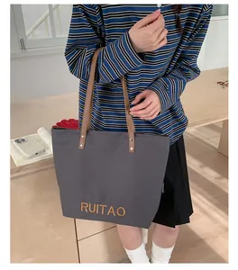 Détail du sac cabas en toile grise avec broderie RUITAO et poignées en cuir