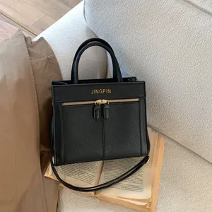 Détail d'un sac à main en cuir grainé noir avec fermetures dorées sur livre