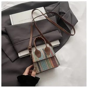 Detail of colorful woven mini bag with brown leather handles in a fashion setting