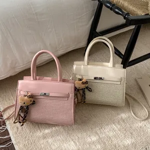 Detail of pink and beige patchwork leather handbag with woven texture and plush charm