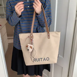 Détail du sac cabas en toile avec broderie de lettres et anses en cuir marron