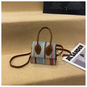 Detail of colorful woven herringbone pattern and brown leather handle on a mini bag