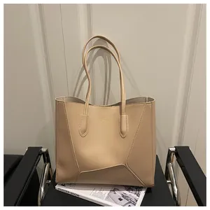 Close-up of beige tote bag with geometric stitching on a black leather chair