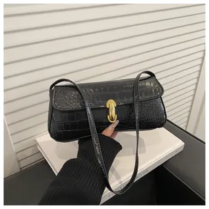 Detail of black crocodile pattern baguette bag with a bright gold oval metal buckle