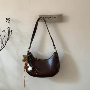 Détail du sac demi-lune marron foncé en similicuir avec breloques cœur et peluche