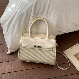 Detail of cream leather and straw woven handbag with metal buckle on wooden floor