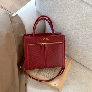 Détail du sac à main rouge foncé avec texture tissée à carreaux et doubles zips