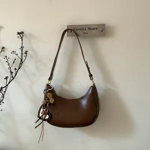Détail du sac croissant marron avec pendentif cœur et boucles métalliques dorées