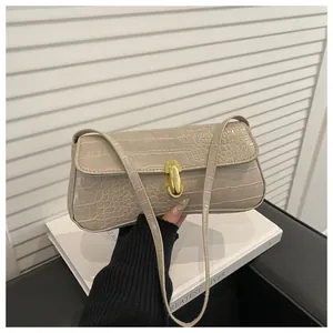 Detail of crocodile embossed leather texture and gold U-shaped buckle on beige handbag
