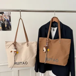 Détail du sac cabas en toile avec poignées en cuir marron et lettrage RUITAO brodé