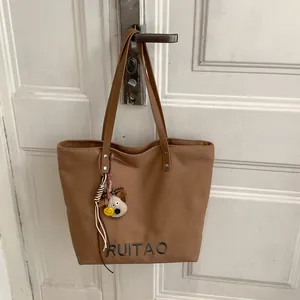 Détail du cabas en toile marron avec broderie RUITAO et porte-clé de dessin animé