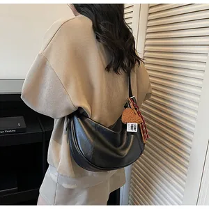 Détail du sac bandoulière croissant noir avec breloque cœur et foulard sur cuir texturé