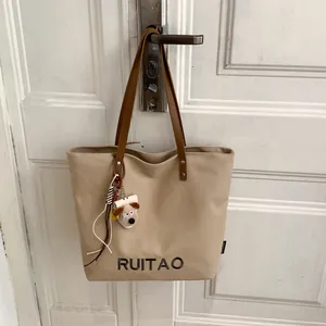 Vue détaillée du sac cabas beige en toile avec broderie RUITAO et breloques en peluche