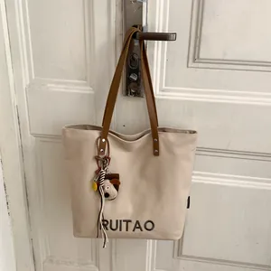 Détail du sac fourre-tout en toile avec lanières en cuir, broderie RUITAO et breloque chiot