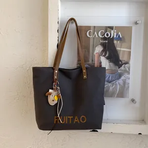 Détail du grand sac cabas en toile grise avec bandoulière et porte-clés mouton