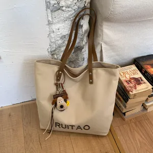 Détail du sac fourre-tout en toile beige avec broderie RUITAO et charm chiot mignon