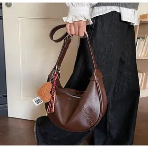 Détail du sac croissant marron foncé avec pendentif cœur en peluche et étiquette