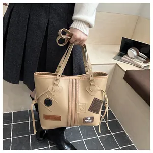 Detail of khaki leather tote bag featuring fashion lucky patches and side drawstring