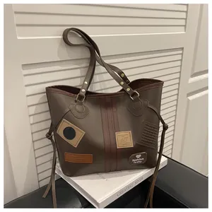 Detail of dark brown tote bag with decorative patches on a book against white shutters