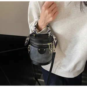 Detailed view of bucket bag with houndstooth silk scarf and gold padlock hardware