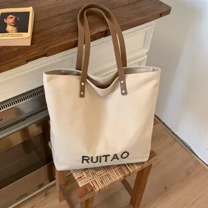 Détail du sac cabas en toile avec bandoulières marron et broderie RUITAO sur bois