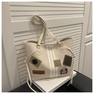 Close-up of cream tote bag with vintage embroidery and long straps against shutters