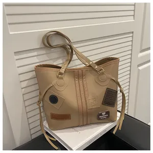 Detailed view of the khaki tote bag with drawstring tassels and decorative heart patch