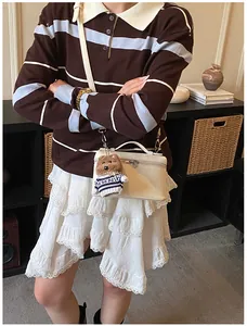 Detalle de un bolso cuadrado de cuero blanco con un adorable colgante de osito