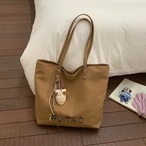 Sac cabas en toile marron avec broderie RUITAO et charm mouton sur sol en bois