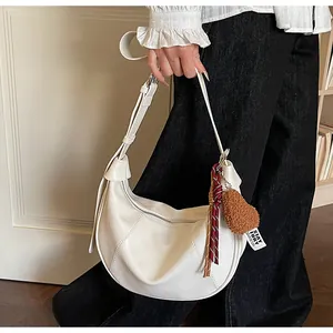 Détail du sac hobo blanc avec breloque cœur en peluche et bandoulière sur modèle