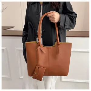 Brown leather tote bag featuring a matching mini pouch and vertical seam detail