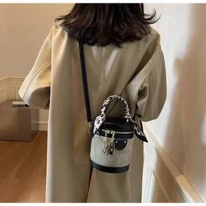 Detail of a vintage-style bucket bag featuring leather-fabric splice and silk scarf handle