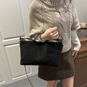 Chic black suede tote bag with brown leather trim and shoulder strap for autumn style