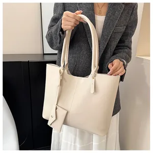 Close-up of cream tote bag with matching coin purse on model in a grey blazer suit