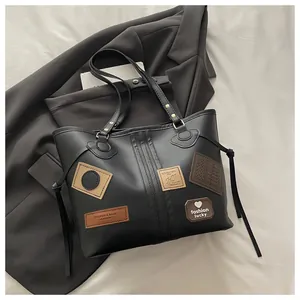 Detail of black tote bag with vintage brown patches and side drawstring accents