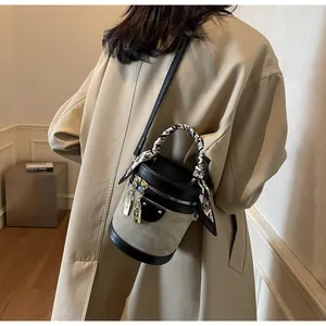 Chic bucket bag with silk scarf handle detail and contrasting leather stitching
