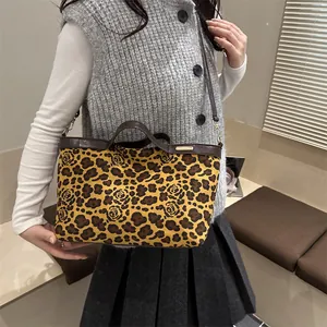 Leopard print canvas tote bag with rose patterns and brown leather handles on a model