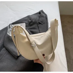 Vue détaillée du sac croissant crème avec bandoulière réglable et fini en cuir texturé