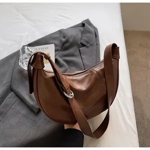 Détail du sac croissant marron foncé montrant la texture cuir et la bandoulière réglable