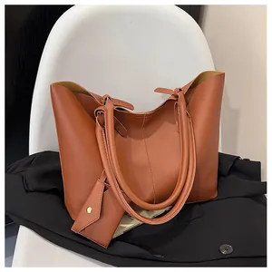Detailed view of the brown leather tote bag with lychee texture and small pendant pouch