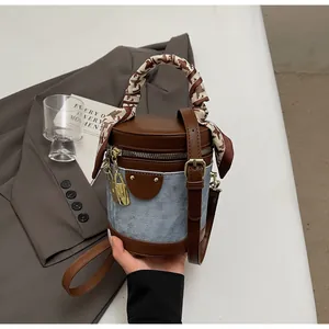 Detail of denim and leather bucket bag with silk scarf handle and golden hardware